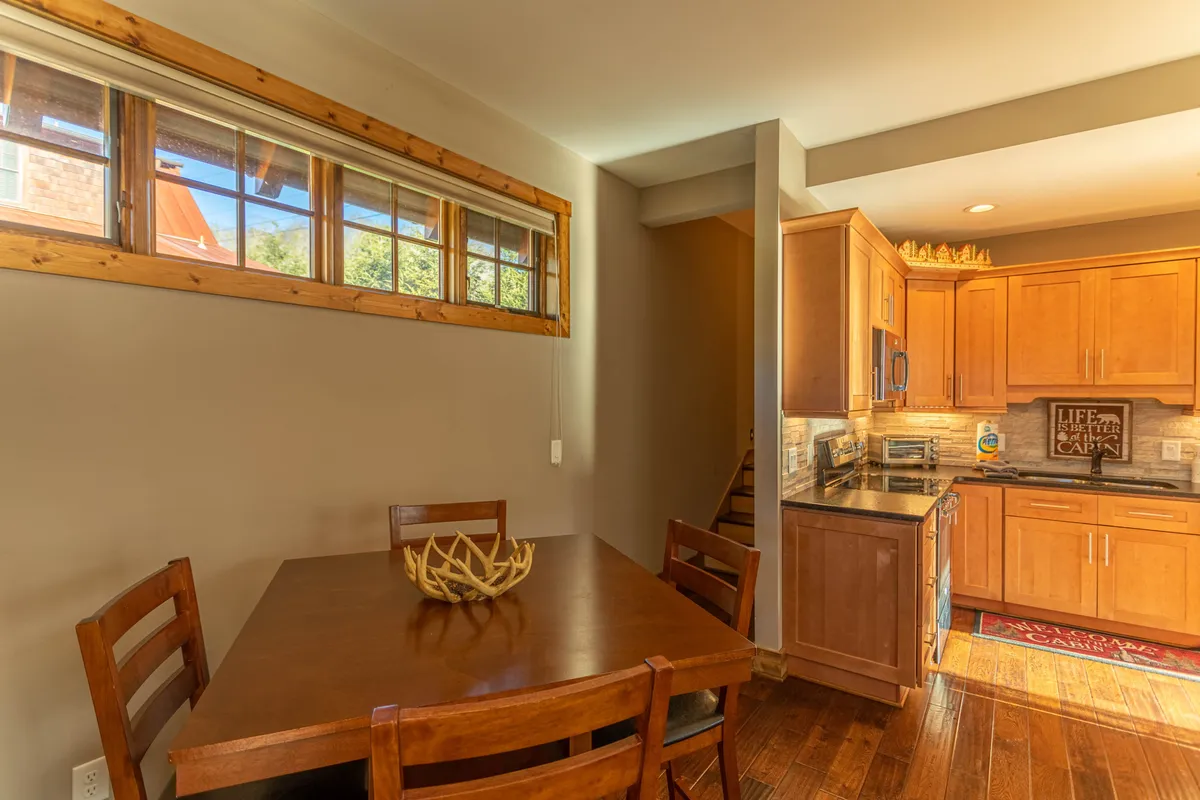 A rustic-chic dining table set against custom cabinetry, adorned with an antler centerpiece and surrounded by warm wooden details. Natural light pours in through nearby windows, creating an inviting setting for family feasts or intimate gatherings.