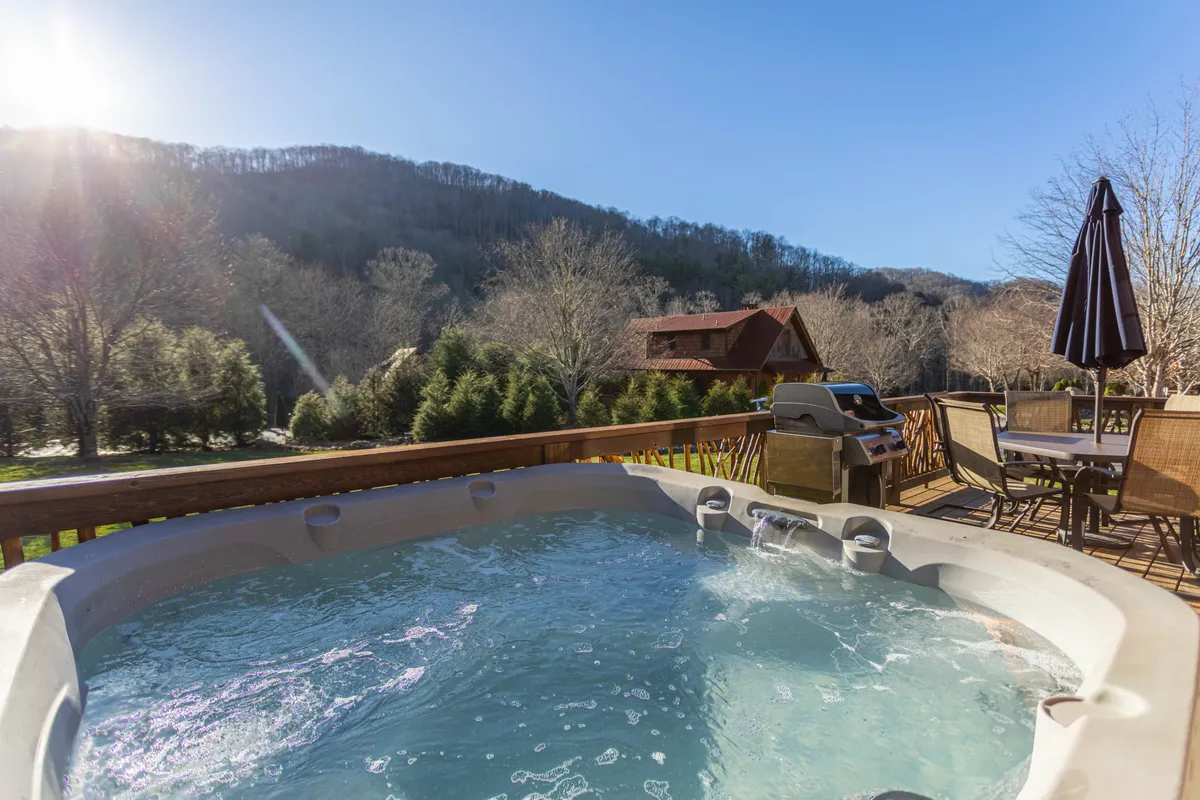 This image features an inviting outdoor hot tub set on a patio, with sweeping mountain views in the background. Patio furniture and a grill enhance the sense of comfort, and the scene radiates serenity—ideal for private relaxation or stargazing at night.